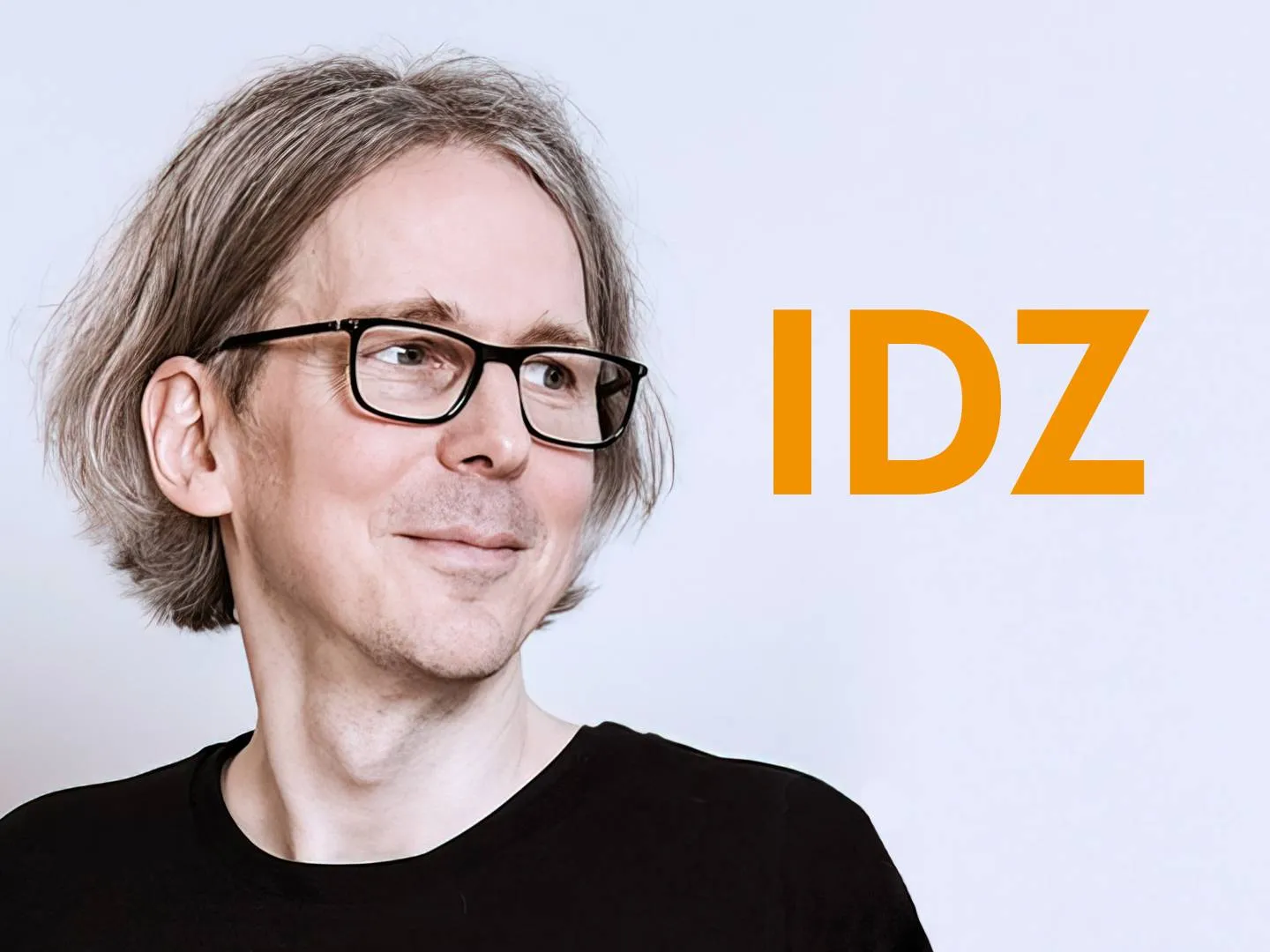 Porträt von Kai gehrmann vor hellem Hintergrund mit IDZ-Schriftzug. Stimmungsvolles Brandingmotiv für Design, Innovation und Thought Leadership.